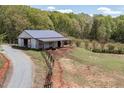 White barn with a metal roof and three stalls on a horse property surrounded by lush trees at 3787 Pleasant Hill Church, Siler City, NC 27344