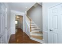 Hallway with light wood stairs, white banister, neutral walls, and doorways into other rooms at 5403 Bayside Ct, Raleigh, NC 27613