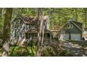 Two-story home with a porch and a detached garage surrounded by lush greenery and blooming flowers at 6105 Splitrock Trl, Apex, NC 27539