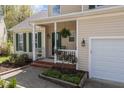 Inviting front porch with hanging plants, landscaping, and a view of the two-car garage at 703 Midsummer Ln, Apex, NC 27502