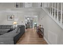 Bright, open living room with hardwood floors, a staircase, and views of the kitchen and a comfortable gray sofa at 8333 Bellingham Cir, Raleigh, NC 27615