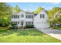 Classic two-story white home with black shutters, complemented by lush green lawn and mature trees at 102 Cockleshell Ct, Cary, NC 27513