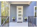 A welcoming front porch with modern white door, black railings, and potted flowers, inviting you into this beautiful home at 107 Hillcrest Ave # C And D, Carrboro, NC 27510