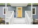 Inviting front porch with bright yellow door, white railings, and a black and white striped welcome mat at 111 Dunstan Ave, Durham, NC 27707