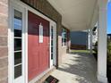 Covered front porch showing brick facade, a cozy swing bench, and the vibrant red front door at 120 Putters Ct, Durham, NC 27703