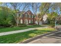 A classic brick home on a manicured lawn with mature trees framing the property at 1216 Caribou Xing, Durham, NC 27713
