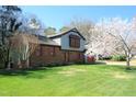 Lovely home with mature flowering tree, brick, siding, and well-kept lawn on a sunny day at 1400 Rainwood Ln, Raleigh, NC 27615