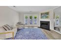 A living room with a fireplace and access to the outdoors features neutral furniture and a blue area rug at 1442 Barton Place Dr, Raleigh, NC 27608