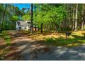 A home's exterior surrounded by lush woods, featuring a long driveway and convenient mailbox at 15 Pine Ridge, Pittsboro, NC 27312