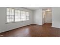 Sunlit living room with wood laminate flooring and a large window with blinds at 1813 Grady Dr, Durham, NC 27712