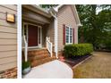 Inviting covered front porch with brick steps and a vibrant red front door at 216 Harvester Dr, Holly Springs, NC 27540