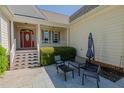 Inviting covered porch with a bright red door and comfortable seating area with an umbrella at 308 Grove Hall Ln, Mebane, NC 27302