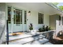 Close-up of the front door with glass panels, stone steps, and a modern exterior light fixture at 4902 Brookhaven Dr, Raleigh, NC 27612