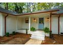 Close-up of a charming white brick home's blue front door with classic lighting fixtures and manicured landscaping at 5312 Woodsdale Rd, Raleigh, NC 27606