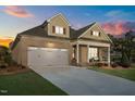 Beautiful exterior of a brick home boasting a two-car garage and covered front porch at dusk at 5733 Mizuno Dr, Fuquay Varina, NC 27526