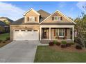 Inviting two-story home with a two-car garage, a brick facade, and a covered front porch at 5733 Mizuno Dr, Fuquay Varina, NC 27526