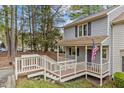 Side view of a cozy home, showcasing a covered porch, American flag, and natural surroundings at 6568 English Oaks Dr, Raleigh, NC 27615