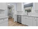 Bright kitchen showcasing white cabinetry, stainless steel dishwasher, and stylish wood flooring at 6568 English Oaks Dr, Raleigh, NC 27615