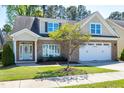 Well-maintained brick home featuring a two-car garage, manicured lawn, and mature tree at 837 Varina Ln, Fuquay Varina, NC 27526