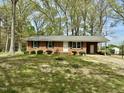 Single story brick home with manicured lawn and mature trees offers classic curb appeal at 1031 Jackson Royster Rd, Henderson, NC 27537