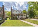 Charming brick home with a covered front porch, featuring dormer windows, under a bright, cloudy sky at 1105 Englewood Ave, Durham, NC 27701