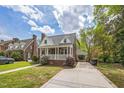 Charming brick home with a covered front porch and convenient carport, all under a bright, cloudy sky at 1105 Englewood Ave, Durham, NC 27701