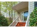 Inviting front entry features a covered porch with white railings and a red painted staircase at 113 Weatherhill Pt, Carrboro, NC 27510