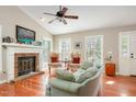 Cozy living room features hardwood floors, a brick fireplace, and large windows providing abundant natural light at 13 Thorne Ridge Dr, Durham, NC 27713