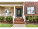 Inviting front porch with brick steps, white railings, and well-maintained landscaping at 2 Piney Ridge Ct, Durham, NC 27712
