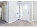 Bright entryway with light gray walls, wood-look floors, a coat closet, and a modern white front door with glass panels at 211 Milky Way Dr, Apex, NC 27502
