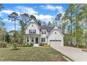 New construction farmhouse with white siding, a two-car garage, black shutters, and a landscaped lawn at 2432 Spindle Ct, Raleigh, NC 27603