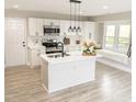 Modern kitchen featuring white cabinets, stainless steel appliances, island with sink, and a cozy window seat at 2824 Wyncote Drive, Raleigh, NC 27603