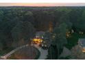 Sunset aerial view of house surrounded by lush trees, with warm lights glowing within at 3016 Allansford Ln, Raleigh, NC 27613