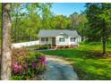 Front exterior of a charming home with a manicured lawn and a gravel driveway surrounded by pink azaleas at 304 Westgate Cir, Angier, NC 27501