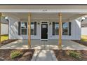 View of front porch with wooden support columns, a black front door, and black shutters at 619 Ray St, Selma, NC 27576