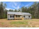 Single-story home with gray vinyl siding, black shutters, a covered porch, and mature trees, creating a serene setting at 6312 Briddle Dr, Wendell, NC 27591