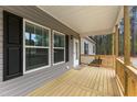 Close-up of the covered front porch with wood railings, gray siding, black shutters, and view of the tree-lined property at 6312 Briddle Dr, Wendell, NC 27591