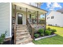 Inviting front porch with stone stairs, wood railings, and charming decorative plants at 810 Mulberry Rd, Spring Hope, NC 27882