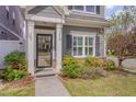 Close-up of home's entrance featuring a black framed glass door, sidelights, and neatly arranged landscaping at 900 Ambergate Sta, Apex, NC 27502