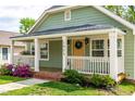 Cozy front porch with detailed trim, decorative lights, and a view of the lush front yard and garden at 1023 Kent St, Durham, NC 27707
