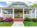 Inviting front porch with white railing, a yellow door with wreath, and blooming flowers adding a pop of color at 1023 Kent St, Durham, NC 27707