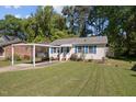 Charming single-story home with blue shutters, a covered carport, and lush green lawn at 105 E Murray Ave, Durham, NC 27704
