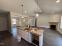Open-concept living space with a modern kitchen island, sleek dark floors and a cozy fireplace at 107 Tee Dr, Selma, NC 27576
