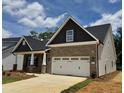 Attractive brick and siding home featuring a two-car garage, covered porch, and well-manicured landscaping at 1075 Fairhaven Dr # 51, Mebane, NC 27302