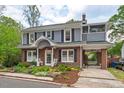 Charming two-story home with a brick facade, grey siding, black shutters and landscaped front yard at 1403 Vickers Ave, Durham, NC 27707