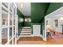 Stylish foyer with green walls, hardwood floors, a staircase, and an open doorway to the living room at 1403 Vickers Ave, Durham, NC 27707
