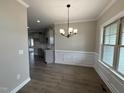 Bright dining room featuring hardwood floors, wainscoting, a modern chandelier, and large windows at 152 Royal Ave, Selma, NC 27576