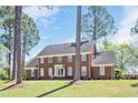 Classic brick home with well-maintained lawn, mature trees, and inviting front entrance with American flag at 1602 Lake Shore Dr, Dunn, NC 28334