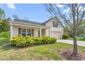 Welcoming single-story home featuring a spacious driveway, manicured landscaping, and charming architectural details at 223 Triumph Dr, Elon, NC 27244