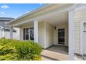 Close-up of a cozy front porch with classic columns, a secure front door, and manicured shrubbery at 223 Triumph Dr, Elon, NC 27244